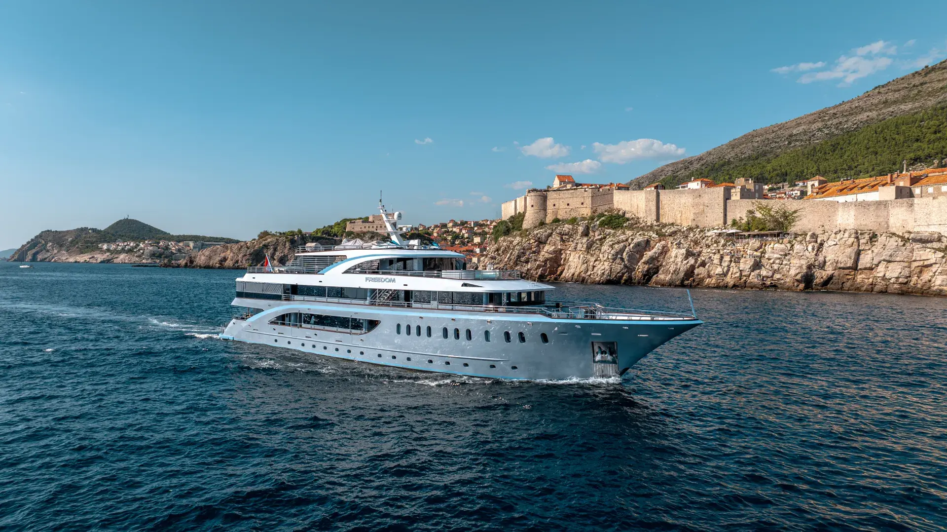 Motor yacht cruising past the Dubrovnik city walls